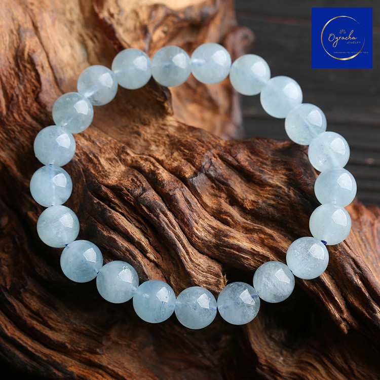 Top-angle view of a stunning aquamarine bead bracelet, displayed on a rustic wooden surface, showcasing its smooth, polished stones. This elegant bracelet from Oyracha Jewelry promotes calmness and clarity, perfect for enhancing your inner peace and style.