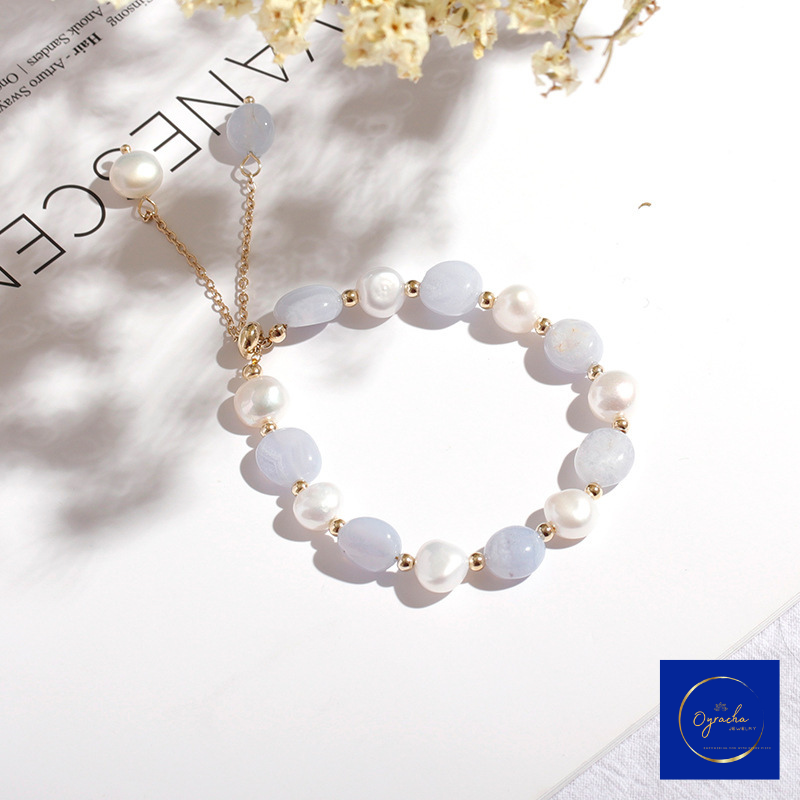 Top angled view of a moonstone and pearl bracelet by Oyracha Jewelry, featuring light blue moonstone and lustrous freshwater pearls with gold bead accents. This elegant bracelet is beautifully showcased in natural lighting, perfect for adding a touch of sophistication to any outfit.