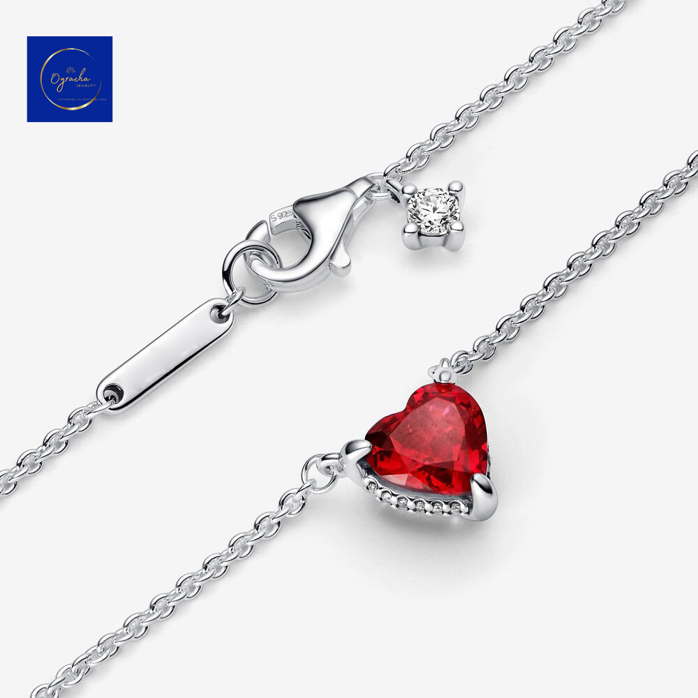 "Close-up angled view of a ruby heart necklace with a silver clasp and chain by Oyracha Jewelry. Featuring a vivid red heart-shaped gemstone, this elegant necklace adds a touch of sophistication to any look. Explore more fine jewelry pieces at Oyracha's collection."

