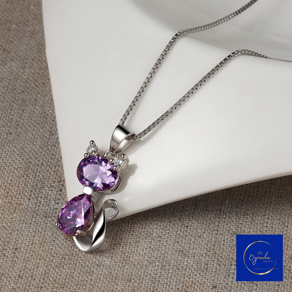 "Charming amethyst cat pendant necklace featuring two purple gemstones in a silver setting, captured from a top-down angle, by Oyracha Jewelry. This elegant piece symbolizes protection and intuition, perfect for those born under the Chinese zodiac sign Dragon. Discover Oyracha's zodiac and gemstone jewelry collection."