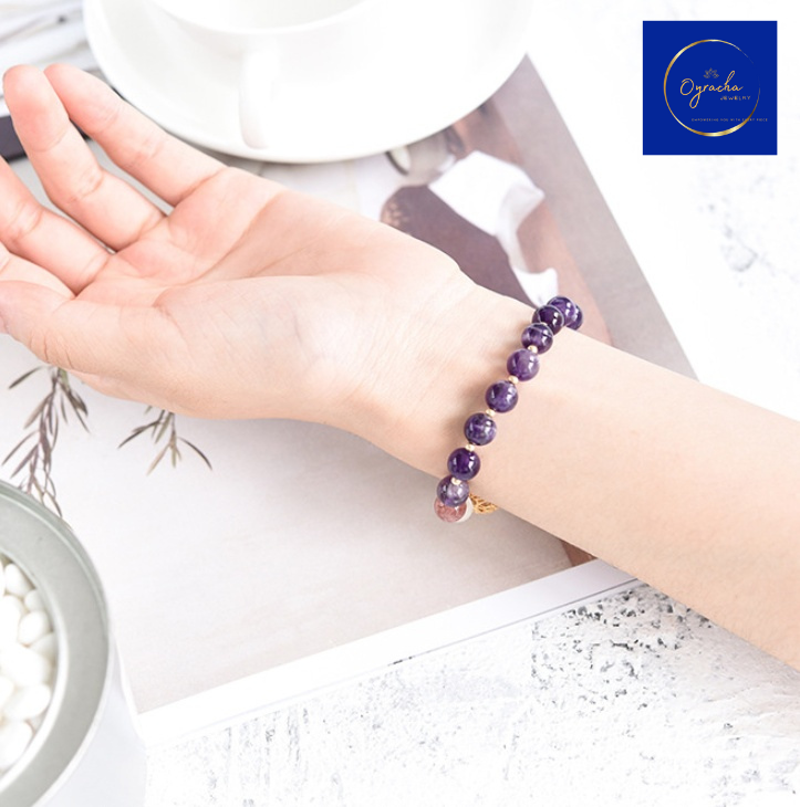 Side-angle view of an elegant amethyst bead bracelet displayed on a wrist, highlighting the natural purple amethyst gemstones and golden accents. Perfect for promoting positive energy and style, available at Oyracha Jewelry.