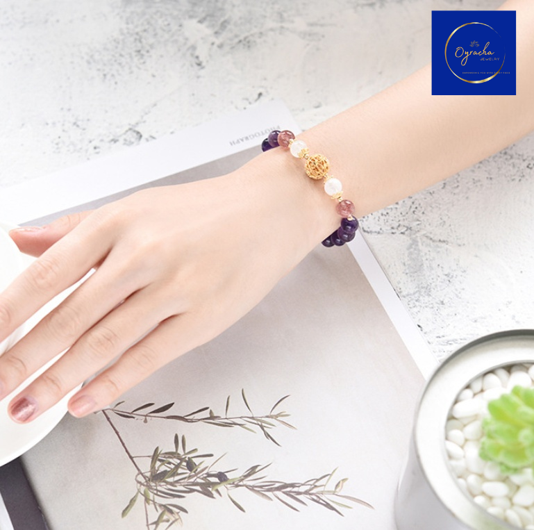 Side-angle view of a stylish amethyst bead bracelet with gold accents and white gemstone details, worn on a wrist, showcasing its luxurious design. Ideal for enhancing positive energy and elegance, available at Oyracha Jewelry