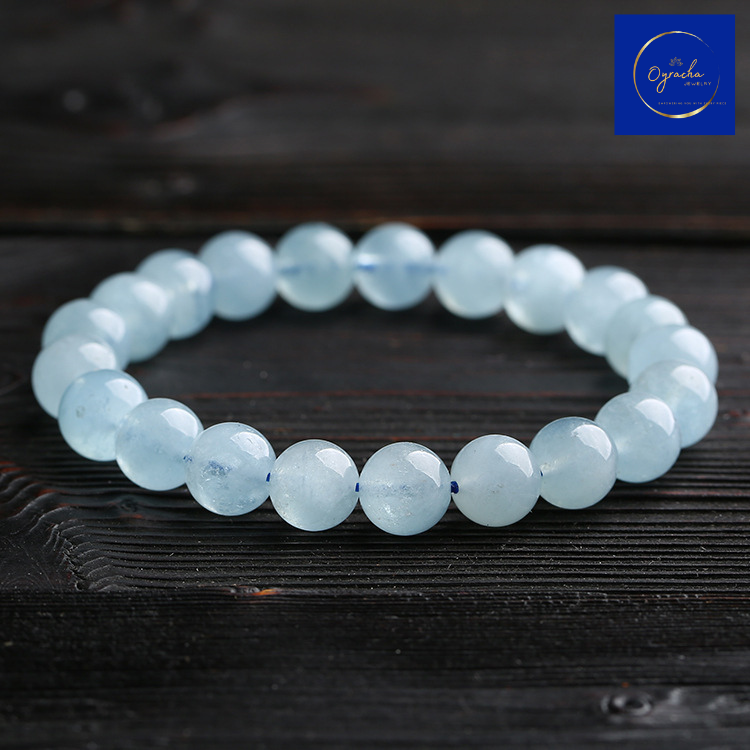 Front-angle view of a polished aquamarine bead bracelet, elegantly displayed on a dark wooden background. This serene aquamarine bracelet from Oyracha Jewelry is designed to promote tranquility and balance, making it a beautiful accessory for any occasion.