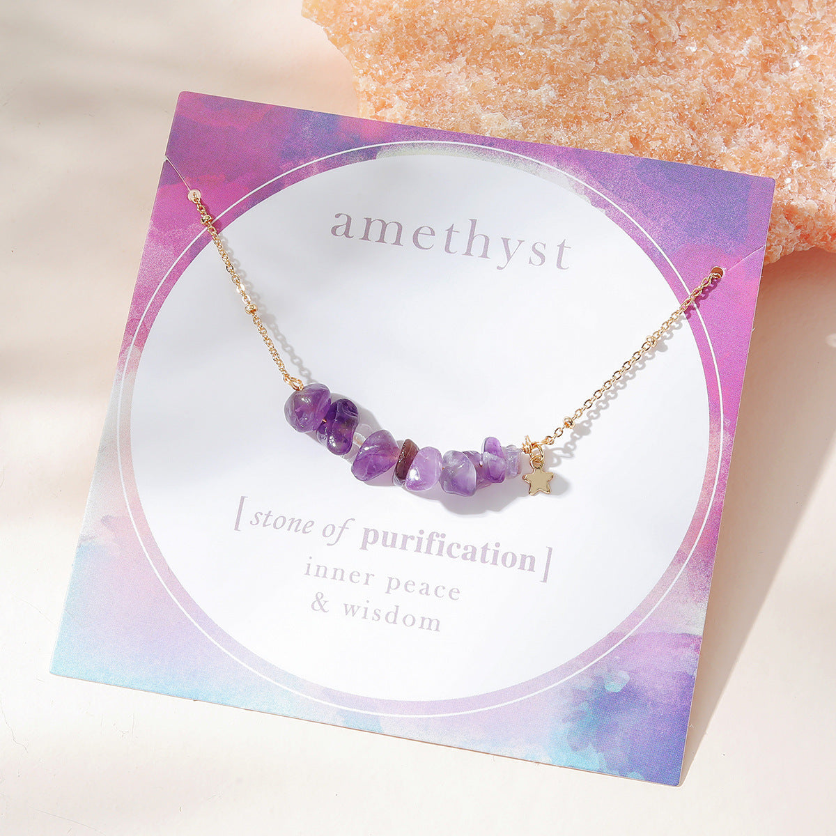 "Top angled view of an amethyst necklace with raw gemstone beads on a delicate gold chain by Oyracha Jewelry. The necklace is displayed on a card highlighting amethyst as the stone of purification, inner peace, and wisdom. A beautiful piece for healing and spiritual balance."

