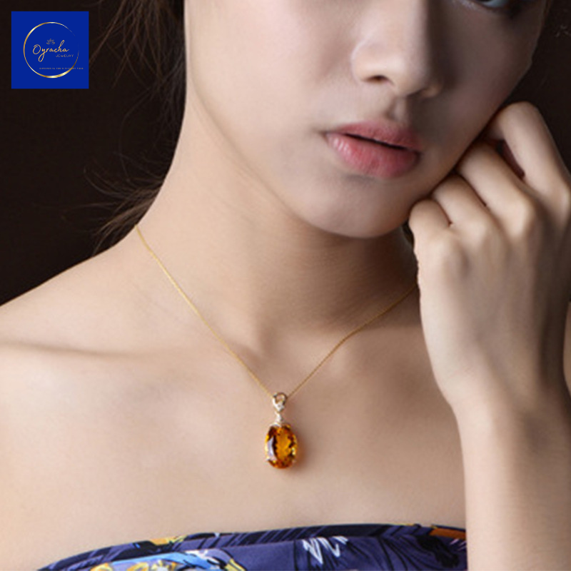 Front view of a model wearing a stunning citrine pendant necklace from Oyracha Jewelry. The oval-cut citrine gemstone is elegantly set in a gold chain, adding a warm glow to the neckline. Ideal for a sophisticated yet minimalist look.