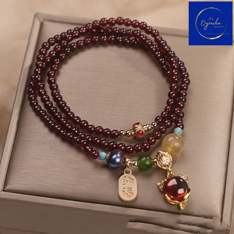 "Elegant multi-strand garnet bracelet adorned with vibrant gemstones and gold charms, captured from a top-down angle view, by Oyracha Jewelry. This unique design embodies prosperity and positive energy, perfect for those who appreciate zodiac-inspired accessories. Discover Oyracha's gemstone and zodiac jewelry collection."