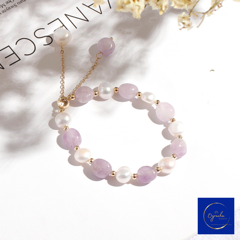 Top angled view of a delicate moonstone and freshwater pearl bracelet by Oyracha Jewelry, featuring soft lavender moonstones and radiant pearls accented with gold beads. The bracelet is elegantly presented on a white surface in soft, natural light, highlighting its timeless design and subtle luxury.