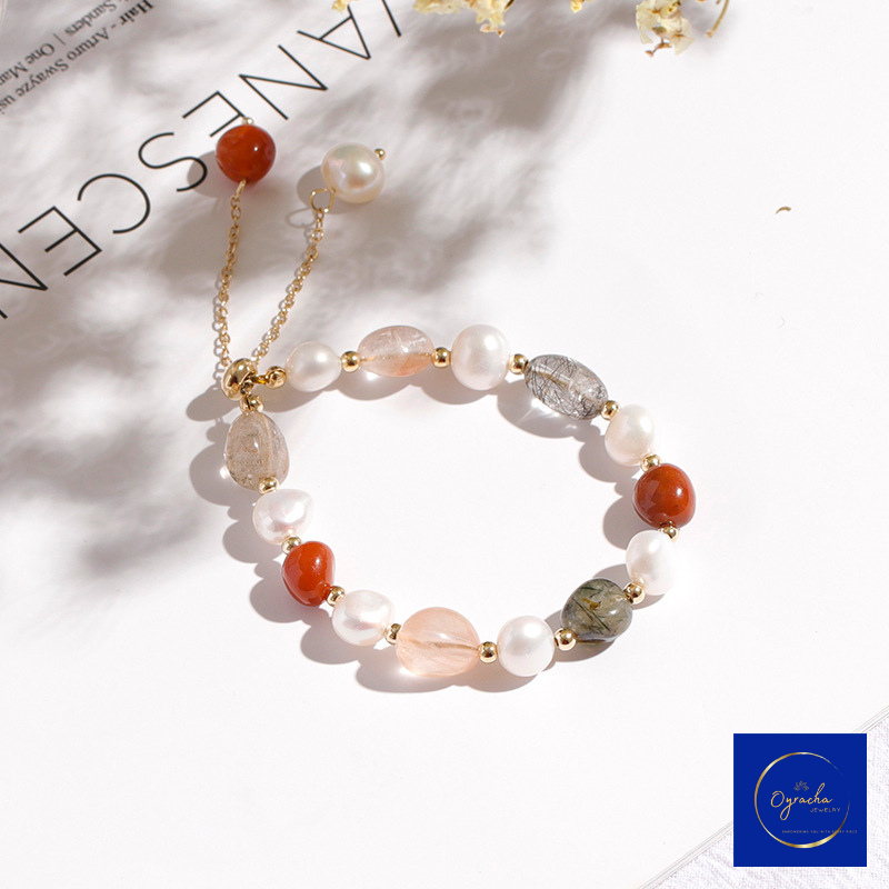 Top angled view of a multi-colored moonstone and freshwater pearl bracelet by Oyracha Jewelry, featuring warm red, grey, and peach moonstone beads alongside luminous pearls and gold accents. Displayed on a minimalist white background, highlighting the bracelet’s elegant and versatile design.